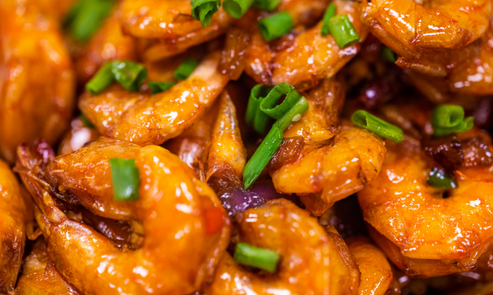 Close-up of Camarones a la Diabla with a vibrant red chili sauce, garnished with fresh green onions, highlighting the bold and spicy flavors of this Mexican dish.