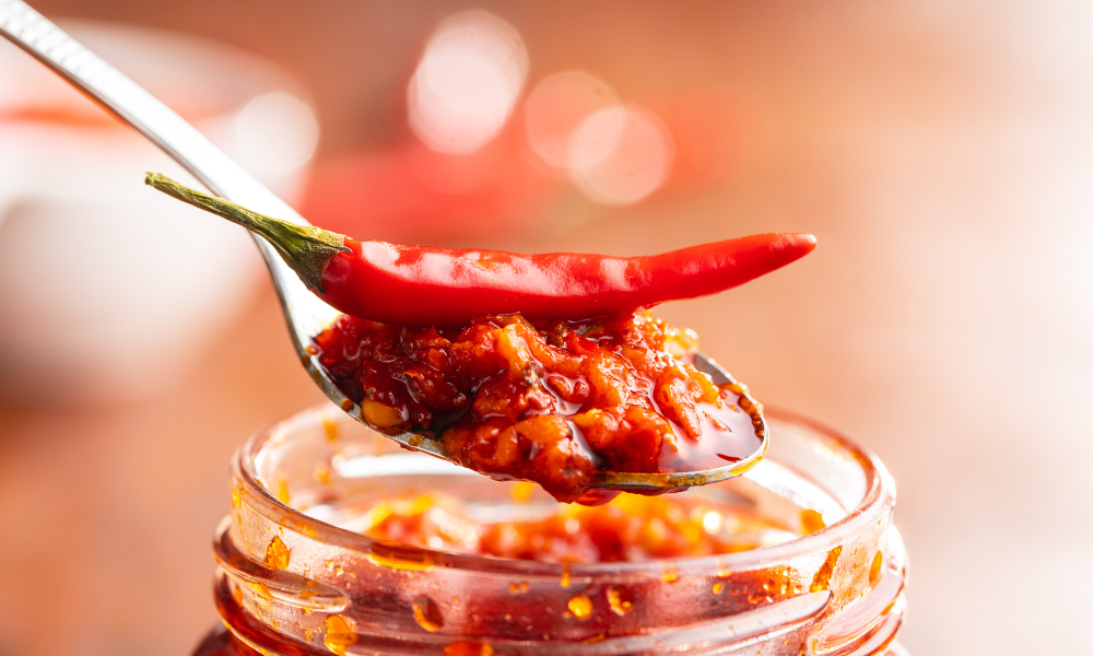 A spoonful of homemade chili paste featuring fresh red chilies, showcasing the key ingredient in the fiery sauce for Camarones a la Diabla.