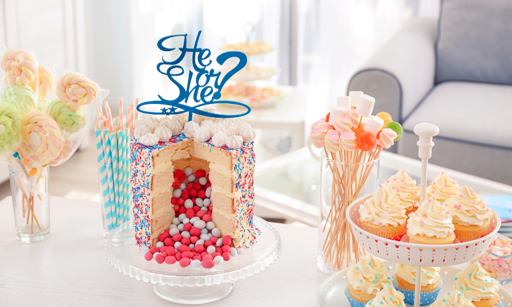 A party cake filled with pink candies, decorated with sprinkles and a "He or She?" topper, surrounded by festive treats and colorful decorations.