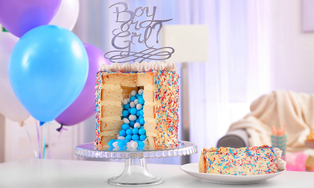 A Gender Reveal Cake with blue candies hidden inside, showcased with balloons and a slice on a plate for a celebratory touch.