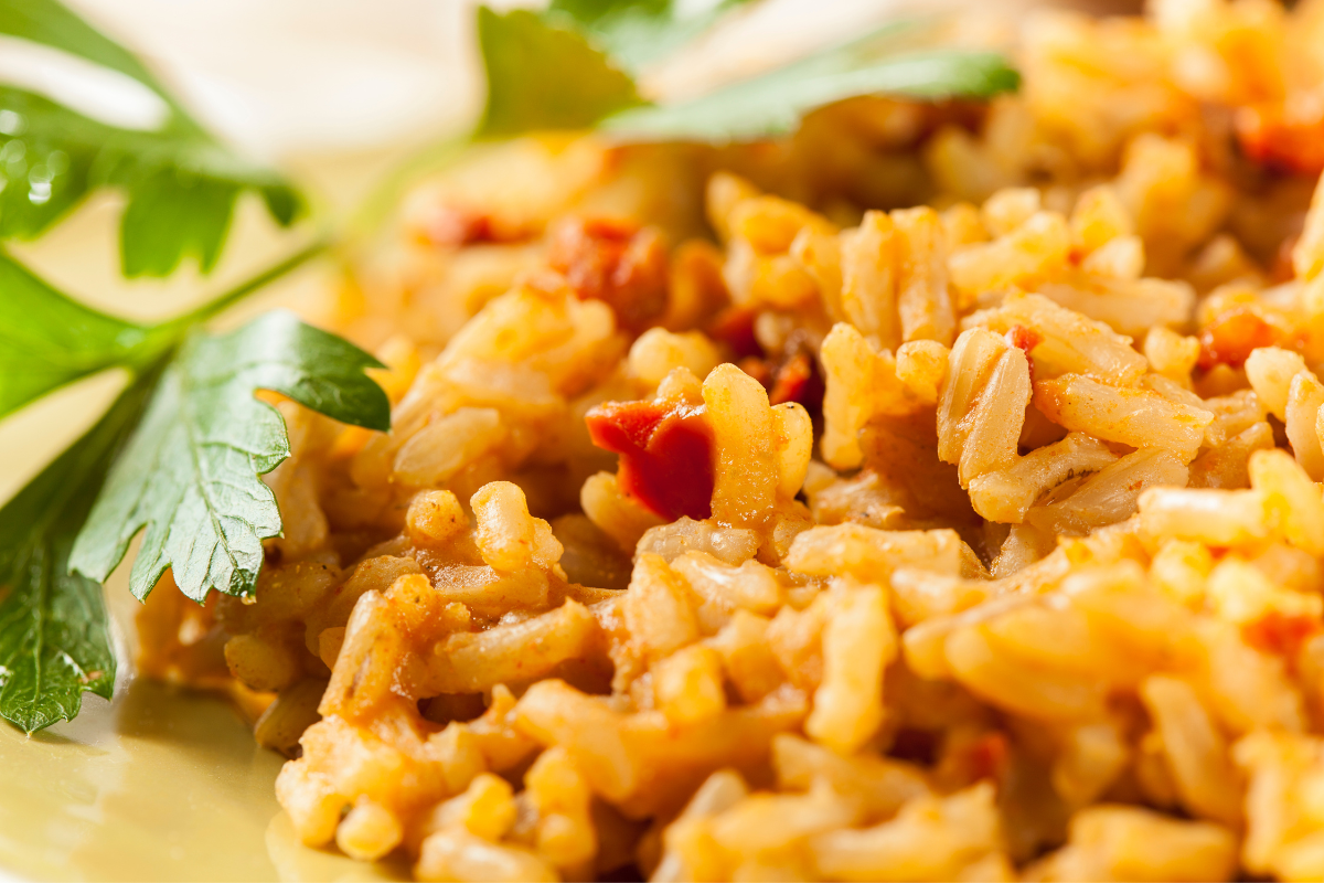 A close-up of tender, golden rice grains mixed with small chunks of red peppers, tomato paste, glistening and ready to serve.