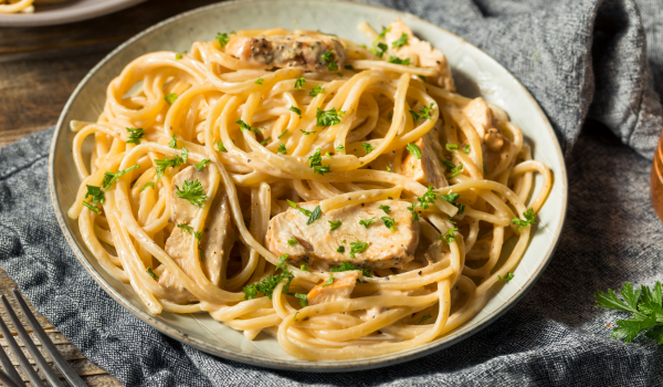 Plate of creamy Louisiana Chicken Pasta topped with fresh parsley, showcasing a rich and luscious cream sauce. Perfect for a comforting, homemade dinner inspired by Southern flavors.