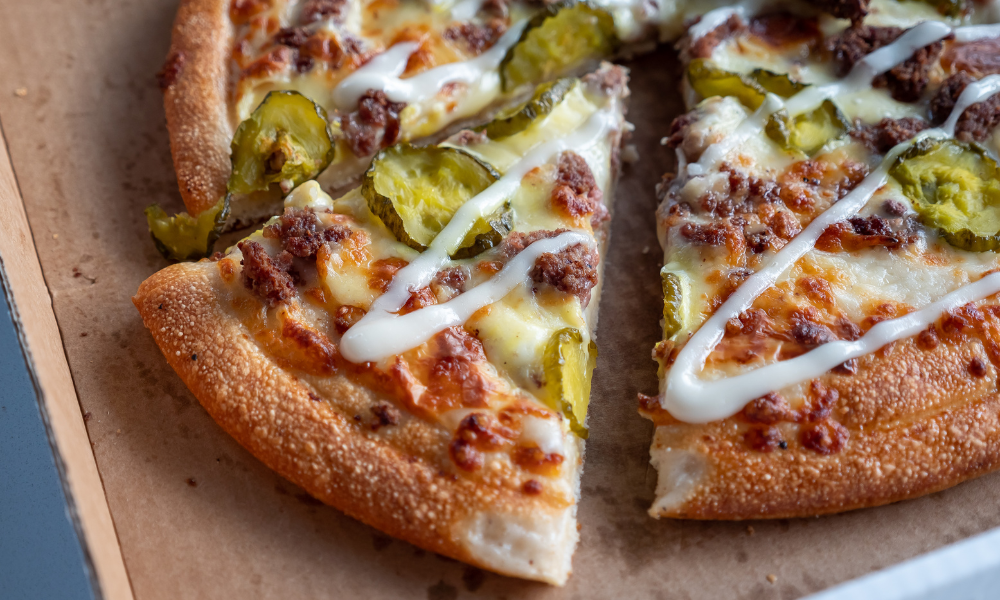 A freshly baked dill pickle pizza pie with crispy crust, melted cheese, and a creamy topping.