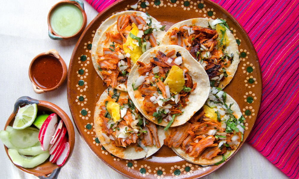 Authentic tacos al pastor served on a traditional Mexican plate with fresh toppings and sauces